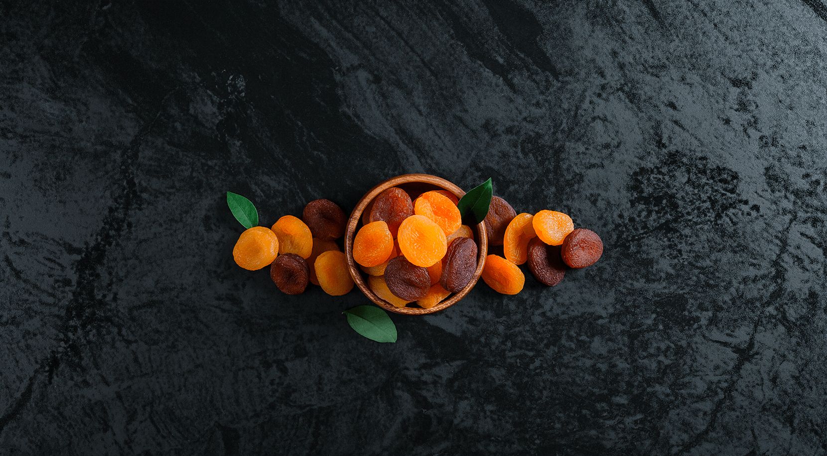 Dried apricots in a bowl on slate